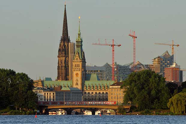 Rathaus Hamburg und Baustelle Elbphilharmonie werden von der aufgehenden Sonne beleuchtet